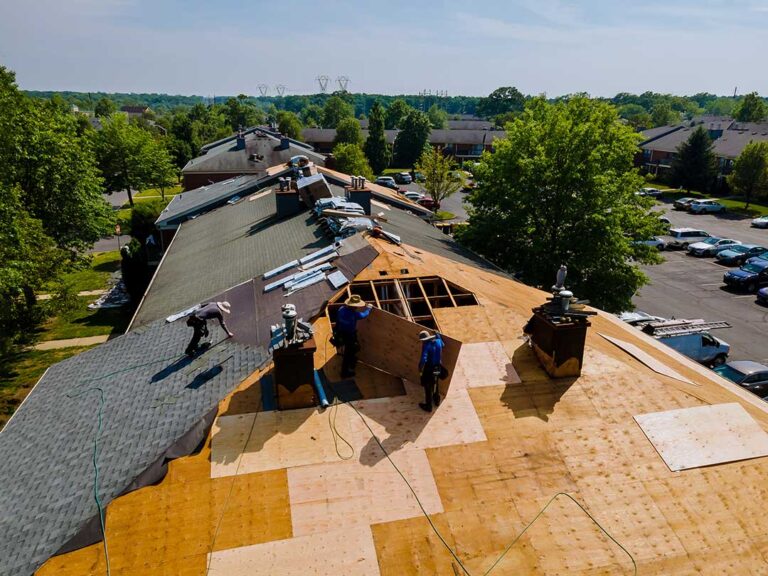 A close-up view of house roof eaves showing gutters, soffits, and fascia under a clear sky.