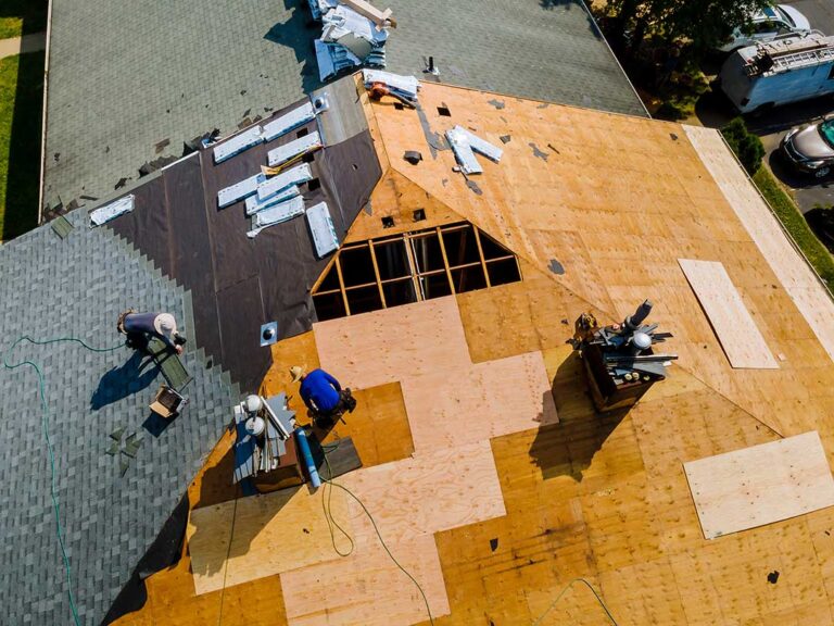 Homeowner examines roof shingles from the ground while checking a ceiling stain inside the house