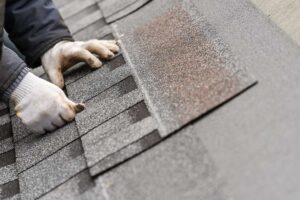Homeowner examining roof shingles with binoculars while standing beside a house.